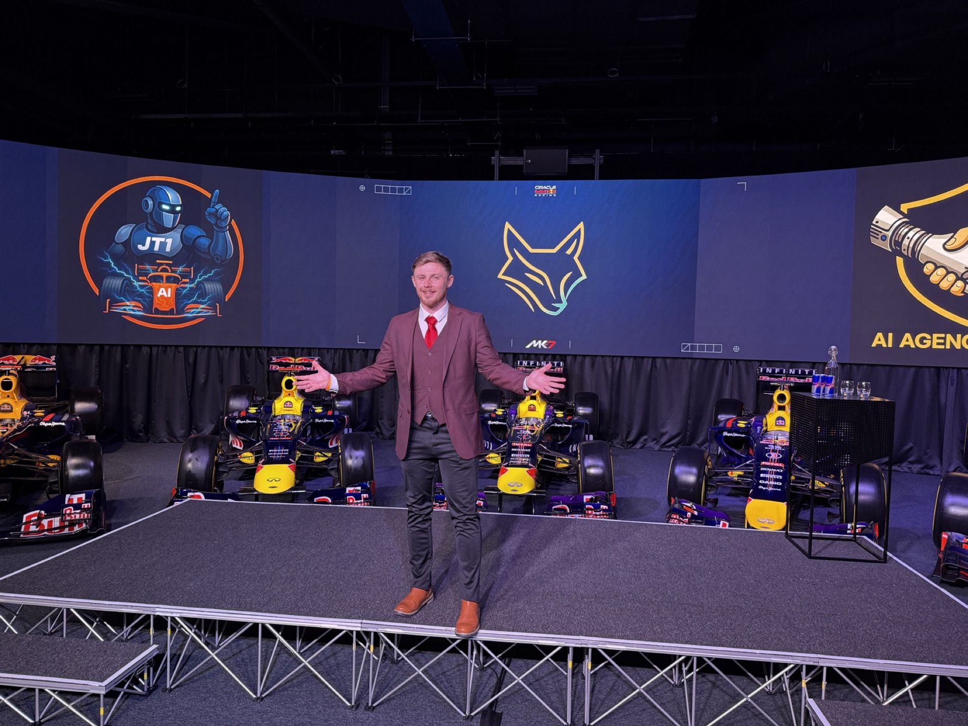 Lewis Hunter on stage at Red Bull Racing with Formula One cars behind him